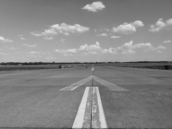 View of airport runway against cloudy sky