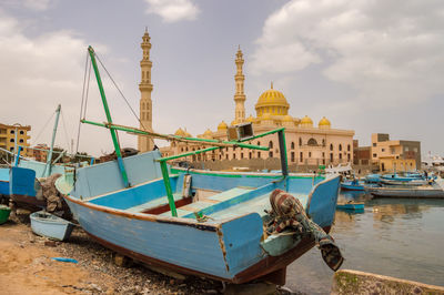 Boats moored at temple against sky