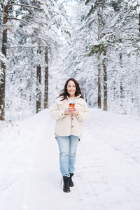 Full length of woman standing on snow covered field