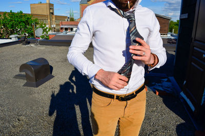 Midsection of man holding umbrella standing on road