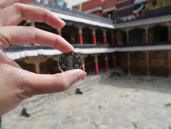 Cropped image of hand holding coin in buddhist temple