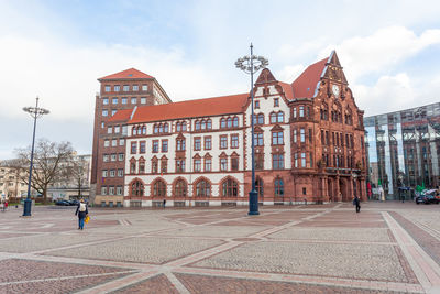 People walking on street by building against sky