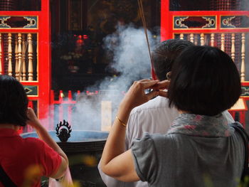 Rear view of people praying at buddhist temple