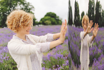 Playful woman reflecting on vehicle trailer at lavender field