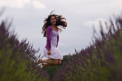 Full length portrait of happy woman jumping amidst lavenders