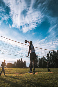 People playing soccer on field against sky