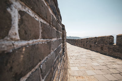 Footpath by wall against sky