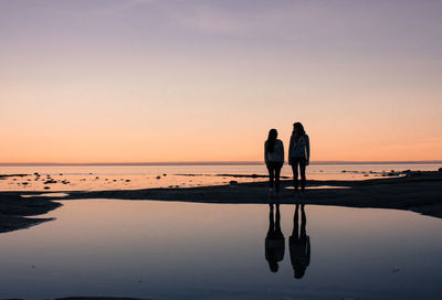 Silhouette people on beach against sky during sunset