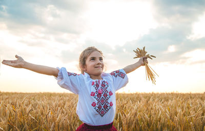 Cute girl holding wheat standing at farm