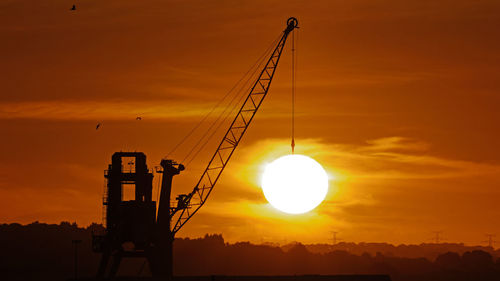 Silhouette crane against sky during sunset