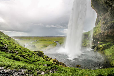 View of waterfall against cloudy sky