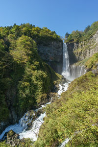 Scenic view of waterfall in forest against clear sky