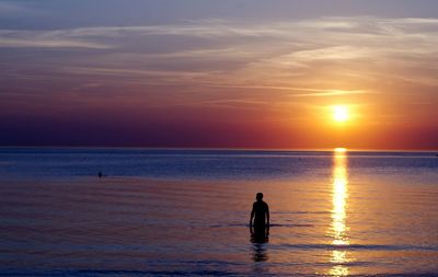 Silhouette people standing on beach against sky during sunset