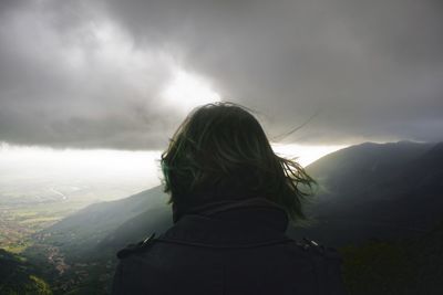 Rear view of woman standing on mountain against sky