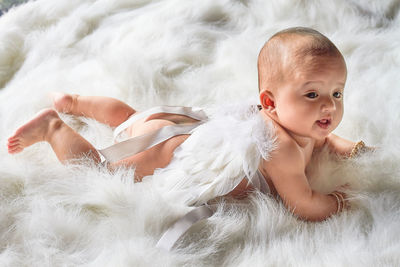 High angle view of cute baby girl lying over fur blanket on bed at home