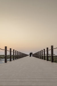 Pier over sea against clear sky during sunset