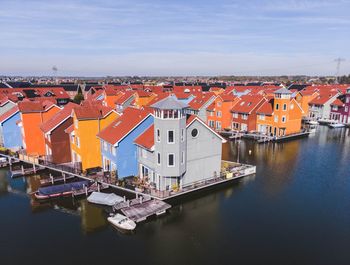 Houses by canal against sky in city