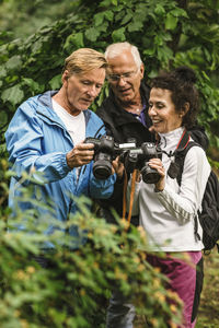 Senior man showing camera to female instructor and friend during photography course