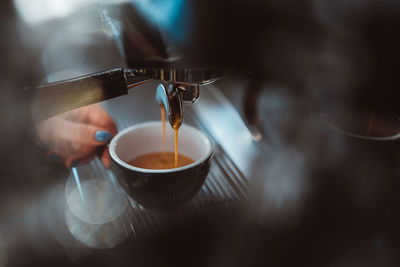 Professional woman barista preparing coffee in a carob coffee machine