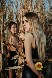 Female friends with long hair standing by plants