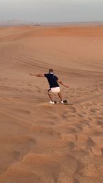 Rear view of man on sand at beach against sky