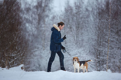 Man and dog standing on snow covered landscape