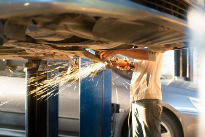 Midsection of mechanic working in auto repair shop