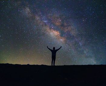 Silhouette of man standing against star field at night