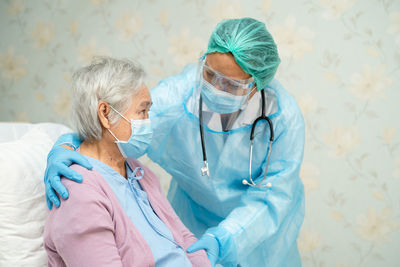 Doctor wearing protective suit consoling patient at hospital