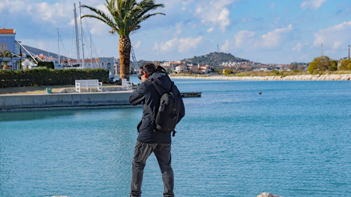 Man photographing by swimming pool against sea