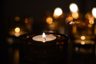 Close-up of illuminated tea light candle in darkroom