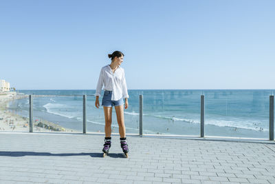 Young woman inline skating on boardwalk at the coast