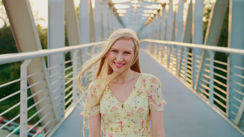 Portrait of smiling young woman against railing