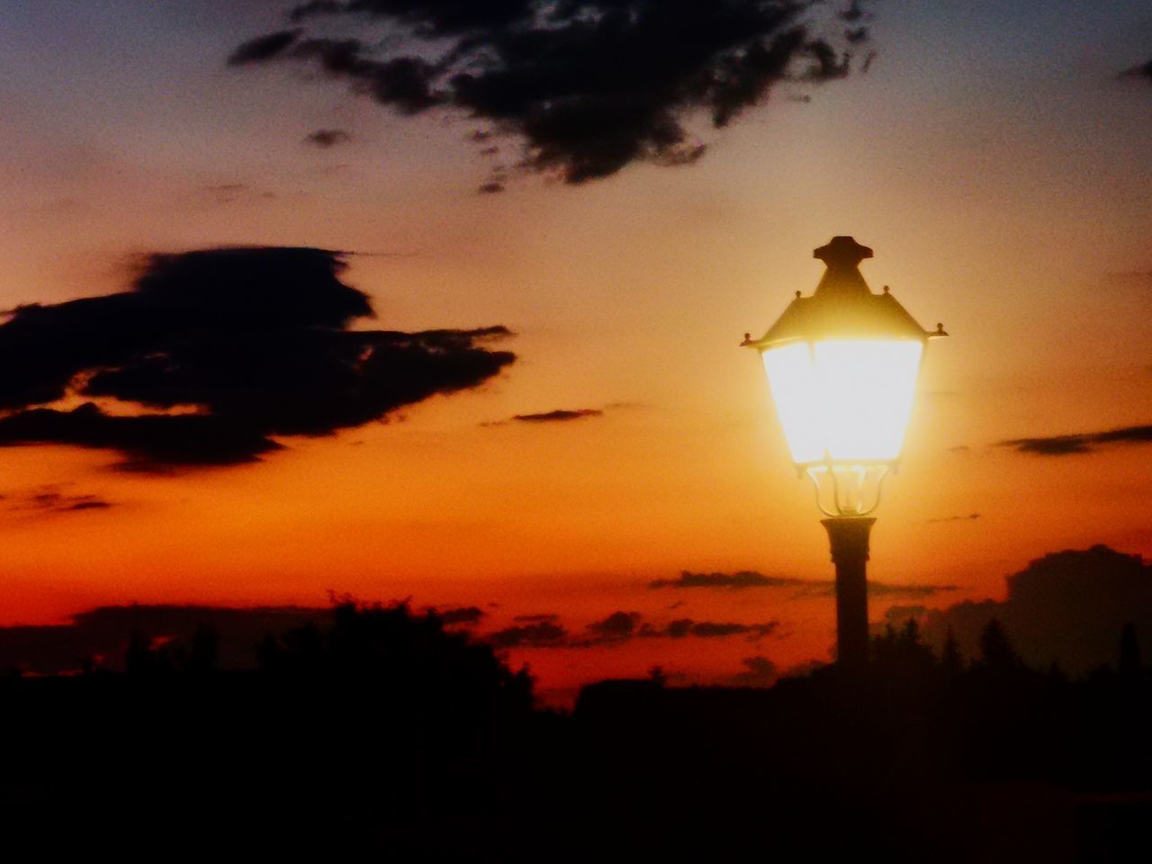 ILLUMINATED STREET LIGHT AGAINST ORANGE SUNSET SKY