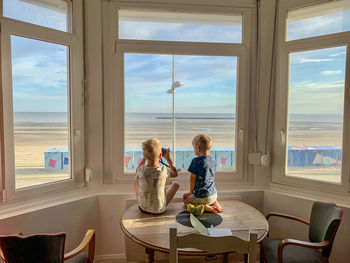 Children sitting on window with the sea