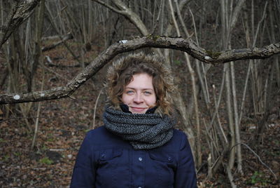 Portrait of smiling young woman standing at forest