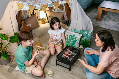 High angle view of mother with children eating barbecue meal at home