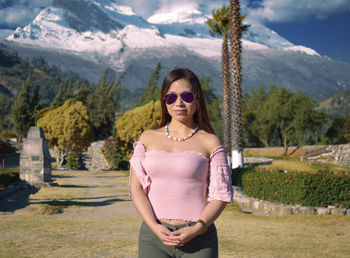 Portrait of beautiful woman standing by mountains