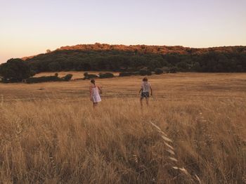 Couple standing on field against clear sky