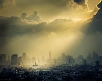 Cityscape against cloudy sky at sunset