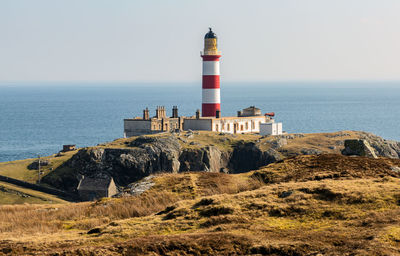 Lighthouse by sea against sky