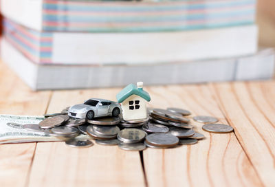 Close-up of car and house models with coins on table