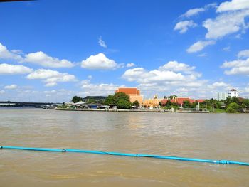 Buildings at waterfront against cloudy sky