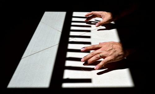 Cropped hands of woman playing piano in darkroom