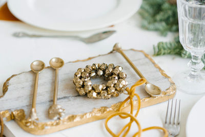 Christmas wreath of golden bells in the decoration of the festive dinner. cutlery on a marble board