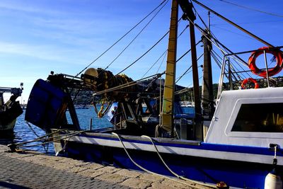 Fishing boat moored at harbor against blue sky