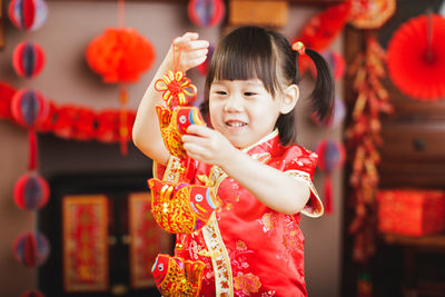 Cute baby girl holding decoration at home