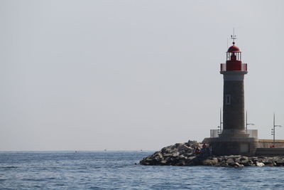 Lighthouse by sea against sky