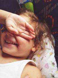 Close-up of smiling girl covering eyes with hand at home