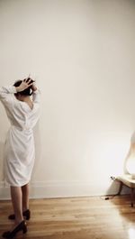 Rear view of woman standing against white wall